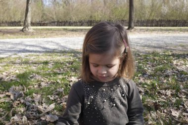 Sonbaharda şehir parkının arka planda güzel küçük kız closeup. Sonbahar mevsimi. Çocukluk kavramı.