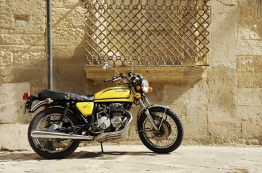 Sarı Honda 400 motorsikleti eski İtalyan şehrinin caddesinde duruyor. Lecce, Apulia, İtalya