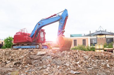 Yerleşim alanındaki bir binanın yıkıntıları üzerinde sürünen buldozer - Sürüngen kazıcı kazısı makinesi yeni inşaatlar için alanı boşaltmak için kova ile alanı temizler - yıkım ve yeniden inşa kavramı