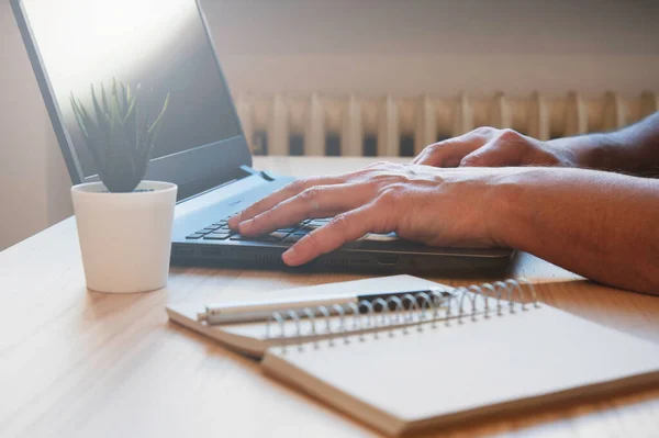 Male hands working on modern laptop - Working at home on the desk with laptop - Freelancer working with pc on the wooden desk at home or in co-working tech area - Smart and remote working concept