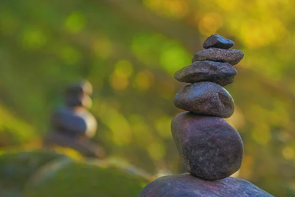 Stacked stone pyramid in front of green blurry background with bokeh — Stock Photo, Image