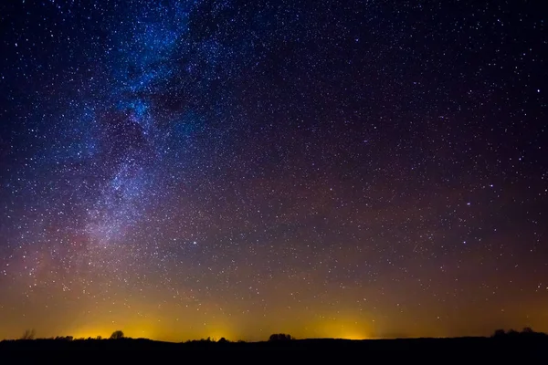 Paisaje nocturno con colorida vía láctea y luz amarilla en el horizonte —  Fotos de Stock