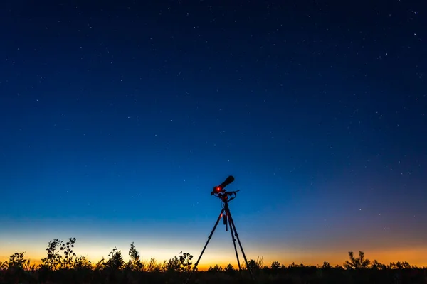 Tripé e uma câmera fotográfica sob céu estrelado — Fotografia de Stock