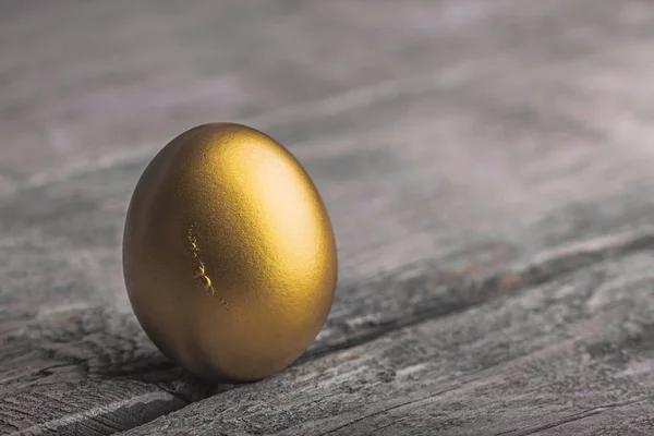 Φόντο χρυσό αυγό σε μια ξύλινη επιφάνεια — Φωτογραφία Αρχείου