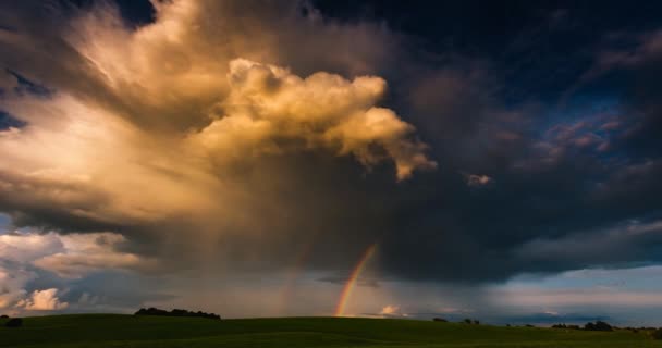 De regenboog gloeit in het zonlicht tegen de achtergrond van donkere wolken. Schaduwen van de zon bewegen langs 4k timelapse — Stockvideo