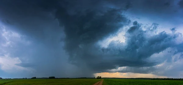 フィールド内の暗い嵐雲の画像 — ストック写真
