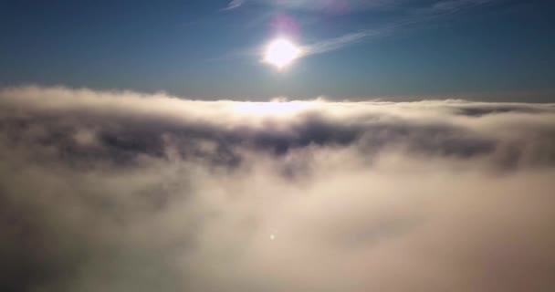 Voler au-dessus de brouillard épais etnuages dans la lumière du soleil avec le ciel bleu, vidéo 4k — Video