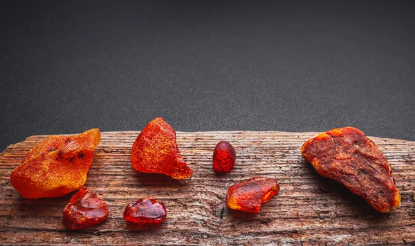 Naturlig Amber. En bit av gult transparent naturlig bärnsten på stor bit av mörkt stenat trä. — Stockfoto