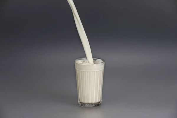 White stream of milk filling faceted glass