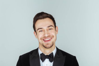 Kameraya düz studio arka plan karşı ciddi görünümlü genç yakışıklı bir adam akşam yemeği ceketli portresi. 