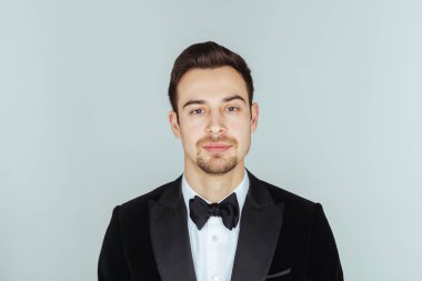 Kameraya düz studio arka plan karşı ciddi görünümlü genç yakışıklı bir adam akşam yemeği ceketli portresi. 