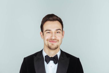 Kameraya düz studio arka plan karşı ciddi görünümlü genç yakışıklı bir adam akşam yemeği ceketli portresi. 