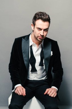 Kameraya düz studio arka plan karşı ciddi görünümlü genç yakışıklı bir adam akşam yemeği ceketli portresi. 