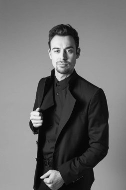 Smokinli genç bir adamın portresi. Stüdyonun arka planında kameraya bakıyor..