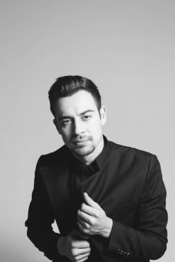 Smokinli genç bir adamın portresi. Stüdyonun arka planında kameraya bakıyor..