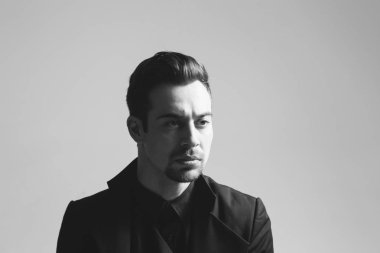 Smokinli genç bir adamın portresi. Stüdyonun arka planında kameraya bakıyor..