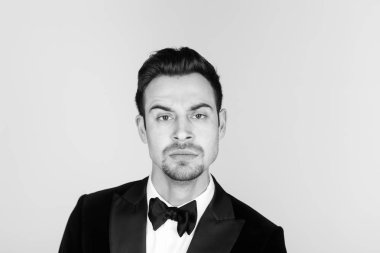 Smokin sinirlenmiş, yakışıklı bir genç adam portresi düz studio arka plan karşı yüzlere çekerek.