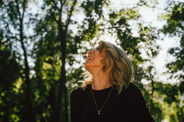 Bir parkta yürüyüş, gülen ve tarafına bakarak bir mutlu sarışın kadın portresi