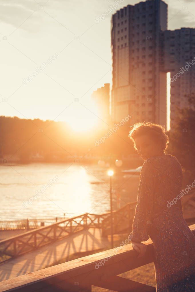 Woman watching the sunset in a park on the river bank
