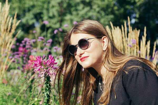 Close up portrait of a woman smells a flower in a city park on a warm sunny day