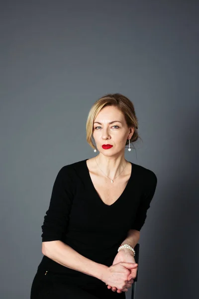 Gri arka plan siyah elbiseli güzel kadın portresi