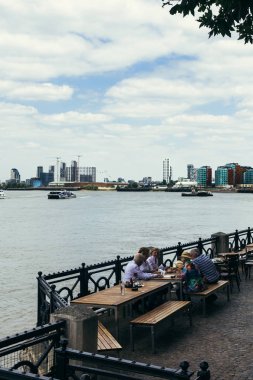 Thames Bank'ta öğle yemeği alan turistler