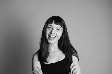 Güzel gülümseyen bir kadının stüdyo portresi, spagetti askısı takan, kameraya bakan, düz gri bir arka plan