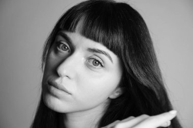 Güzel esmer bir kadının stüdyo portresini kapat, kameraya bak, düz gri bir arka planda.