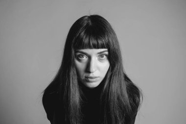 Güzel esmer bir kadının stüdyo portresini kapat, kameraya bak, düz gri bir arka planda.