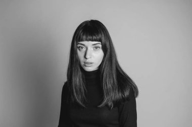 Güzel esmer bir kadının stüdyo portresini kapat, kameraya bak, düz gri bir arka planda.