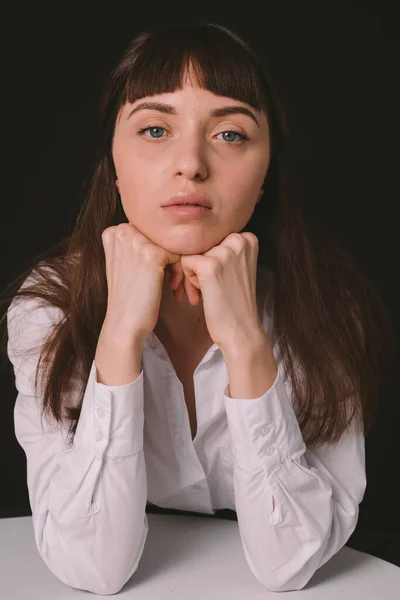 Студийный Портрет Красивой Брюнетки Белой Рубашке Сидящей Столом Обычном Черном — стоковое фото