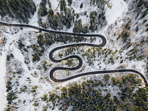 Winding road from high mountain pass, in winter time. Aerial view by drone . Romania