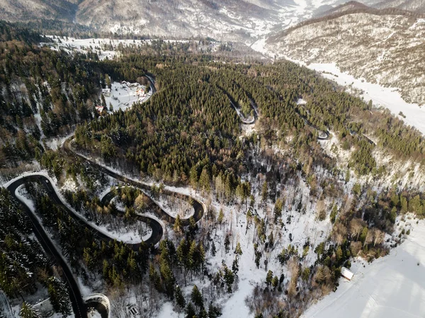 Winding road from high mountain pass, in winter time. Aerial view by drone . Romania