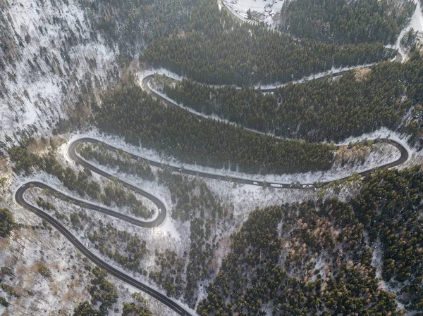 Winding road from high mountain pass, in winter time. Aerial view by drone . Romania