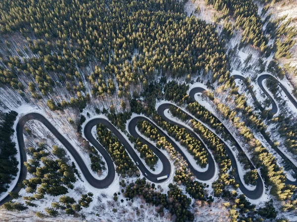 Winding road from high mountain pass, in winter time. Aerial view by drone . Romania