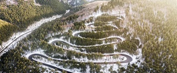Winding road from high mountain pass, in winter time. Aerial view by drone . Romania