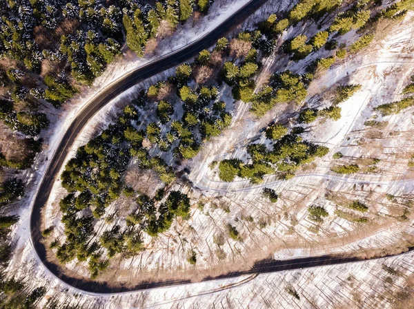 Winding road from high mountain pass, in winter time. Aerial view by drone . Romania