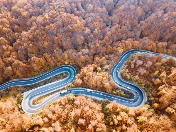 Winding road from high mountain pass, in autumn season.