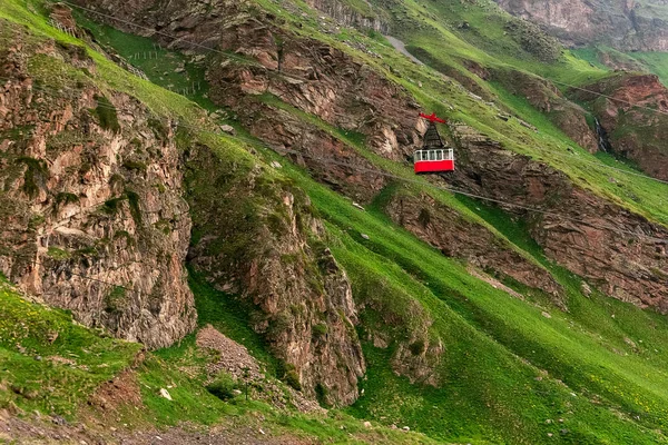 Ropeway in Caucasus Mountains. Red cable car moves down iron cable. Beautiful mountain landscape of Caucasus.