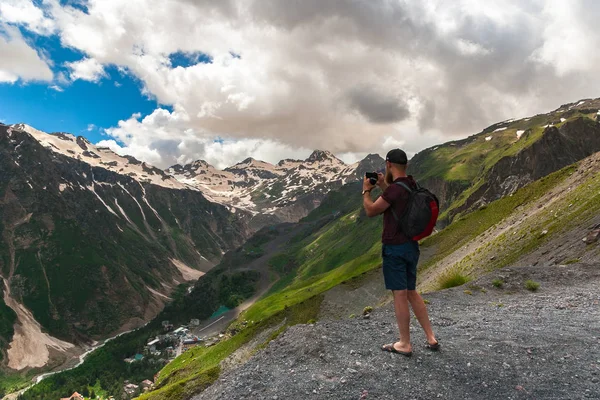 Toerist met rugzak staat op de top van plateau en foto's bergen. Kaukasus gebergte, kloof Baksan — Stockfoto