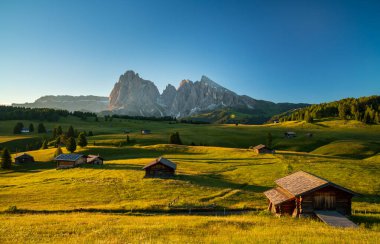Seiser Alm 'da Chalets, arka planda Langkofel Dağı ile yüksek irtifa çayırı, gündoğumunda Dolomitler, Güney Tyrol, İtalya