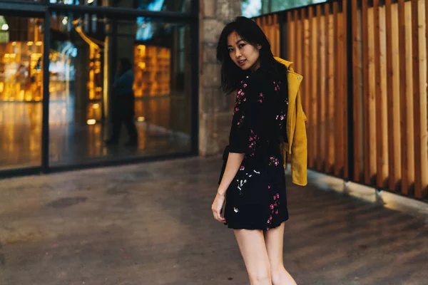 年轻的亚洲妇女穿着迷你礼服回看相机在她的方式到购物中心 — 图库照片