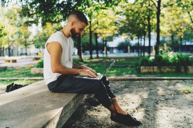 Hndsome genç adam ile bir dizüstü bilgisayar dışında oturan