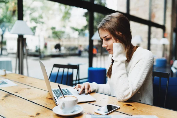 时髦的女孩滚动网站 而网上冲浪互联网上的笔记本电脑在早上的咖啡休息 — 图库照片