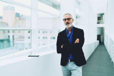 Profesyonel avukat istemcileri office koridorda bekleyen gözlüklü. Akıllı arıyorum erkek parlak koridorda ofis pencere yanında dururken kamera bakarak sakallı yaşlı