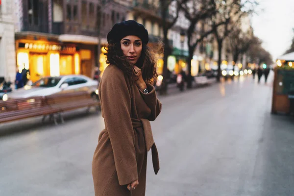 ファッションのブロガーの女性ビジネス旅行中に新しい街を探索しながら道路を横断トレンディな服を着てします コートとベレー帽の夜で 通りを歩いて身に着けている留学生女の子 — ストック写真