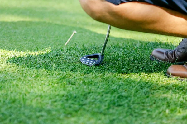 Golfer marks the ball during the tournament plays with the club on the field — Stock Photo, Image
