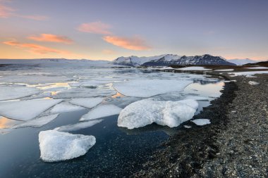Buzul Lagoon buzdağları okyanusa siyah elmas plaj, Jokulsarlon, İzlanda, soyut şekilleri oluştururlar. Gün batımında muhteşem manzara.