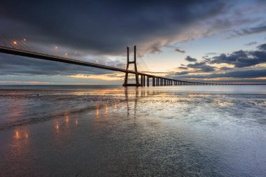 Vasco da Gama Köprüsü manzarası gün doğumunda. Dünyanın en uzun köprülerinden birisidir. Lizbon muhteşem bir turistik yerdir çünkü ışığı, anıtları vardır. Portekiz tarihi.