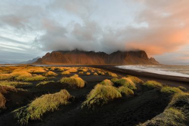 Vestrahorn Dağları ve gün doğumunda İzlanda'da Siyah kum tepeleri Büyülü manzara. Renkli bir deniz manzarası stokksnes headland panoramik görünümü.